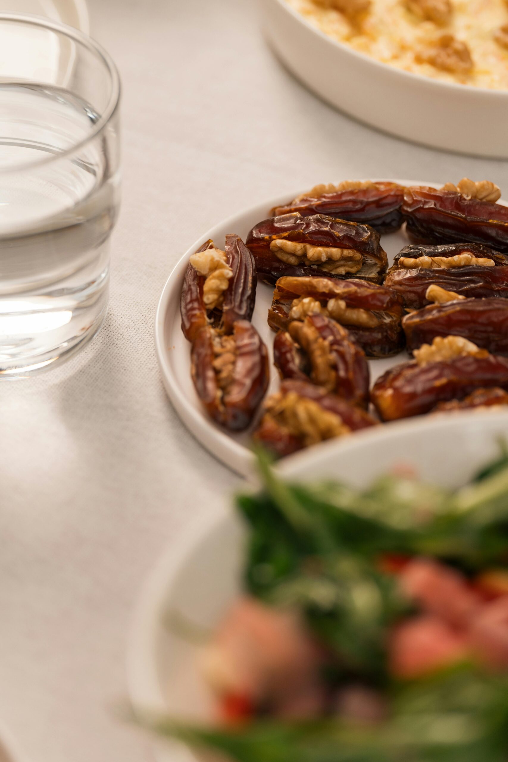 A close-up shot of a plate of dates with walnuts, a bowl of salad, and a glass of water, ideal for Ramadan Iftar settings.